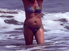 Una donna matura si mostra in spiaggia e riceve un'eiaculazione inaspettata sui suoi genitali non depilati