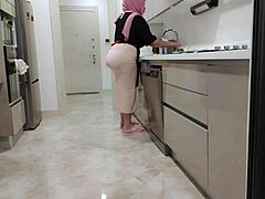 La madrastra con grandes pechos se levanta mientras cocina para su hijastro