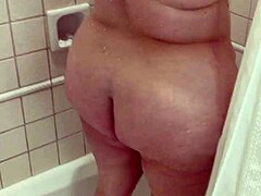Amateurvrouw met grote natuurlijke borsten en kont neemt een douche in onze hotelkamer